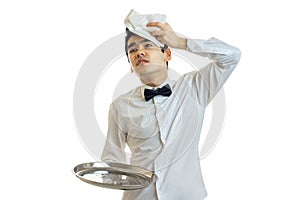 The young weary waiter holding a tray is empty and put on the head of a towel