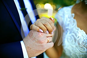 Young wedding couple, bridegroom and bride, holding each others hands and showing wedding rings.