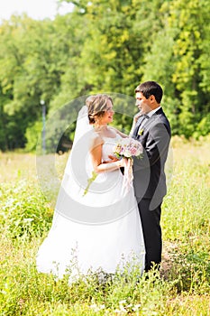 Young wedding couple enjoying romantic moments outside on a summer meadow