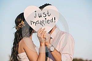 young wedding couple kissing and holding heart with just married