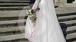 Young wedding couple walking near palace in park. Bride and groom in luxury royal place upping the stairs