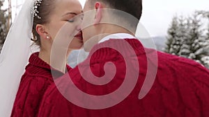 Young wedding couple walking, smiling and talking holding hands in snowy forest during snowfall. Winter wedding