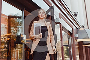 Young well dressed business woman with tablet pc leaving corporate building, hotel