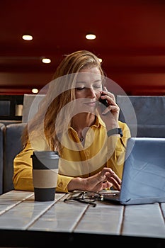 young attractive blond cauasian woman sitting at coffe shop, working on laptop photo