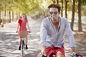 Young white adult couple riding bikes on a quiet sunny road