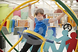 Young white boy in science centre using a human gyroscope