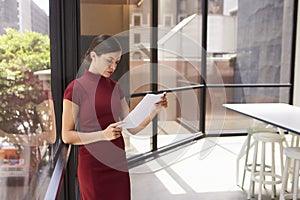 Young white businesswoman reading document in modern office