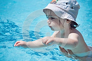 Mladý bílý kavkazský batole nošení klobouk plavání v lázně bazén bytí podporované podle jeho rodič 