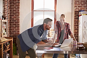 Young white couple using laptop computer in their kitchen