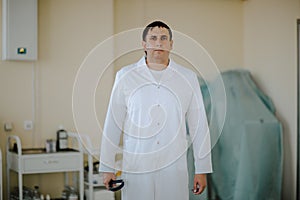 Young white doctor with stethoscope posing at white operation room. Copy space