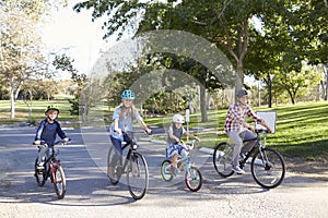 Young white family cycling together through a park