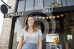 Young white female business owner standing outside cafe