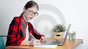 A young white female student working hard using a laptop preparing for exams or making homework at home