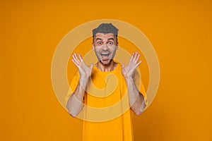 Young white man expressing surprise and gesturing isolated over yellow background