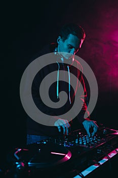 Young white man performing as a DJ in night club. Professional disk jokey mixing vinyl records on a concert