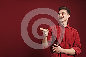 Young white man wearing shirt pointing finger aside and laughing