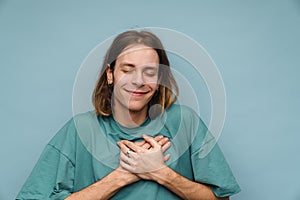 Young white man wearing t-shirt smiling and holding hands on his chest