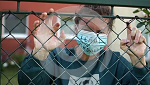 Young white woman behind bars with the inscription on the mask. I cant breathe. Knocks on the fence, aggression look