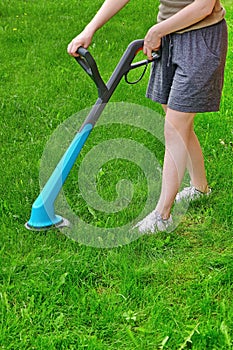 Young White Woman Holding A Corded Grass Trimmer