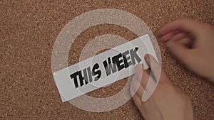 A young white woman pins a white paper titled `This Week` to a corkboard for better time management