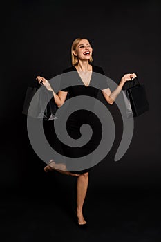 Young white woman posing with shopping bags isolated over black background