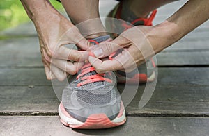 A young white woman ties laces on her running shoes