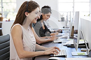 Young white woman working at computer in office with headset