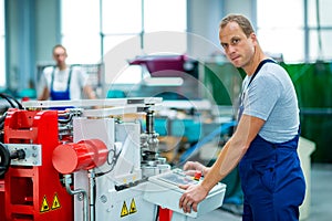 Young white worker in factory using machine