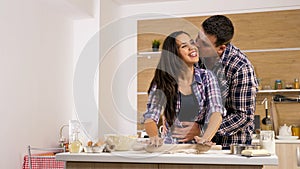 Young wife giving affection to her husband while cooking