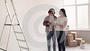Young wife and husband choosing decoration ideas for new apartment, discussing redesigning house with design plan