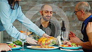 Young wife putting tasty chicken on the table