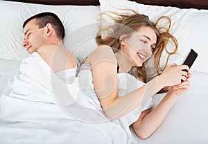 Young wife texting with lover on smartphone