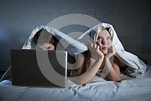 young wife upset unsatisfied and frustrated in bed while husband work on computer laptop ignoring her