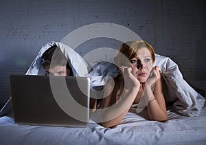 young wife upset unsatisfied and frustrated in bed while husband work on computer laptop ignoring her