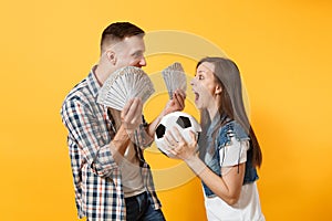 Young win couple, woman man, football fans holding bundle of dollars, cash money, soccer ball, cheer up support team