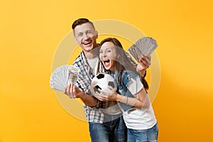 Young win couple, woman man, football fans holding bundle of dollars, cash money, soccer ball, cheer up support team