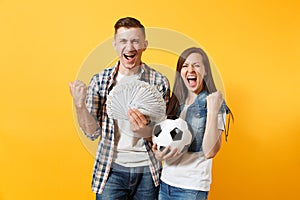 Young win couple, woman man, football fans holding bundle of dollars, cash money, soccer ball, cheer up support team