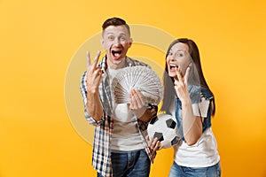 Young win couple, woman man, football fans holding bundle of dollars, cash money, soccer ball, cheer up support team