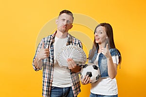 Young win couple, woman man, football fans holding bundle of dollars, cash money, soccer ball, cheer up support team