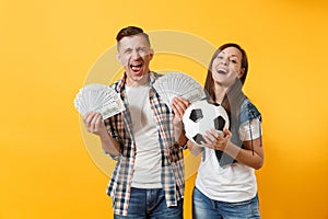 Young win couple, woman man, football fans holding bundle of dollars, cash money, soccer ball, cheer up support team