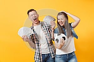 Young win couple, woman man, football fans holding bundle of dollars, cash money, soccer ball, cheer up support team