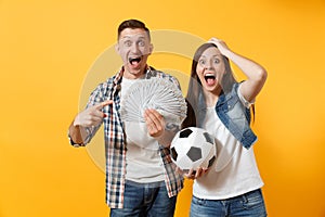 Young win couple, woman man, football fans holding bundle of dollars, cash money, soccer ball, cheer up support team