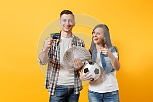 Young win couple, woman man, football fans holding bundle of dollars money, credit card, soccer ball, cheer up support