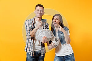 Young win couple, woman man, football fans holding bundle of dollars money, credit card, soccer ball, cheer up support