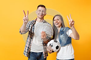 Young win couple, woman man, football fans holding bundle of dollars, cash money, soccer ball, cheer up support team