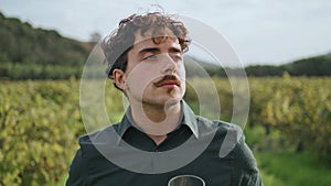 Young winemaker standing vineyard enjoying smell exquisite white wine close up.