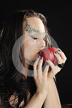 Young witch kissing a red apple