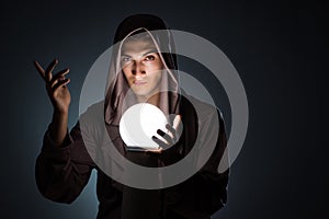 The young wizard with crystal ball in dark room