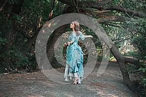 A young woman in a 19th century dress runs away along a forest path, a mystical atmosphere. Historical costume. Woman in a park or