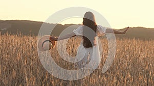 Young woman 25-30 years old with long hair in a wheat field on a summer day